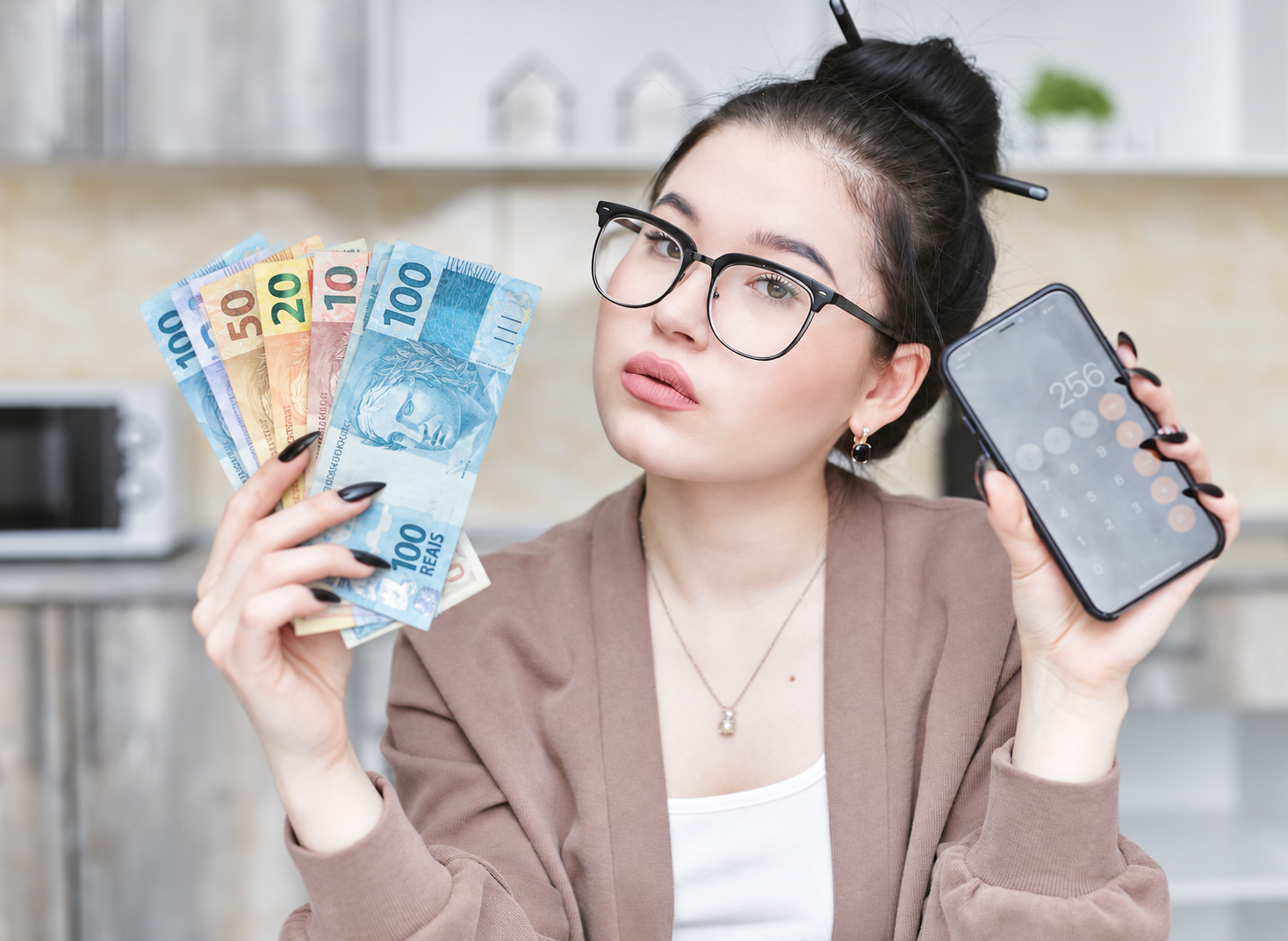 Pessoa com celular e cédulas de reais representando ganhos por vendas